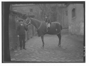 Die Tochter der Fotografin auf einem Reitpferd, gehalten vom Stallknecht