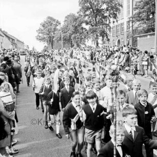 Kindervogelschießen: Umzug: Hamburger Straße: Jungen mit Blumenstäben und Fähnchen, Mädchen mit Blumenbögen: rechts Theodor-Mommsen-Schule: an den Straßenrändern Zuschauer, 7. Juni 1968