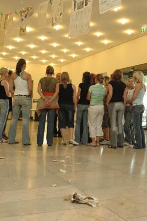 Besucher im Foyer unter einer Bespannung mit Zeitungsblättern
