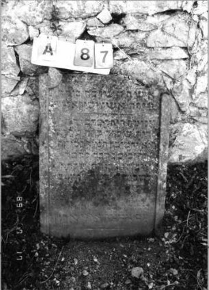 Grabstein 87 (Index: 99798157) Material: Sandstein, rot Zustand: stark verwittert Maße HxBxT: 79x59x10 cm Beschreibung: Stele, geschwungener Abschluß Besonderheit: Namensakrostichon: Grabstein 87A