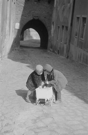 Zwei kleine spielende Mädchen mit einem Puppenwagen