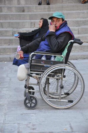 Barcelona - Behinderter im Rollstuhl bettelt : Vor der Kathedrale sitzt ein behinderter Mann in seinem Rollstuhl und bettelt Passanten an. Aufgenommen am 15. April 2012 in Barcelona