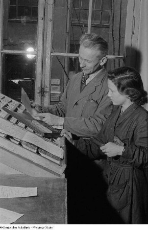 Meister mit Lehrling beim Schriftsetzen