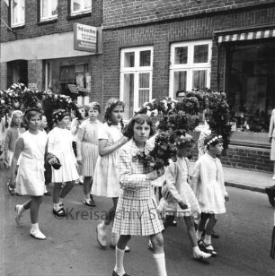 Kindervogelschießen: Umzug: Hindenburgstraße: Mädchen mit Blumenbögen: hinten Häuser mit Schaufenster, Werbeschild "Miele", 17. Juli 1967