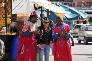 Auf dem Platz Djemaa el-Fna : Zwei marokkanische Männer versuchen einer Touristin in Marrakesch ihre Rasselinstrumente zu erklären, aufgenommen am 02.11.2008