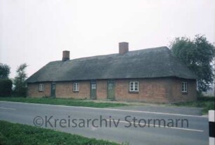 Altfresenburg 5: traufständige Landarbeiter-Mehrfamilienkate, Backsteinmauerwerk mit Reetdach: Straßenfront mit Eingangstüren, Giebelseite