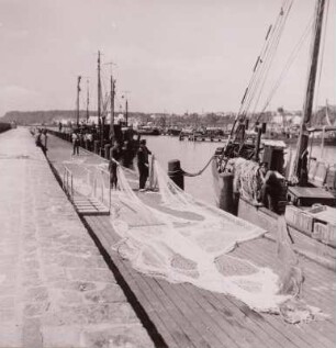 Saßnitz. Fischereihafen, Fischer bei Netzarbeiten am Kai, um 1960