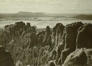 Sächsische Schweiz. Die vorderen Schrammsteine (Friedrich-August-Felsen, Schrammtorwächter, Dreifingerturm). Blick nach Südwesten auf den Großen (links) und Kleinen Zschirnstein. Dahinter der Hohe Schneeberg