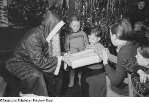 Weihnachtsmann beim Überreichen von Geschenken an Kinder auf der Weihnachtsfeier des VEB Kartographie