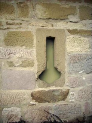 Evangelische Pfarrkirche - Kirchhof im Südwesten - ehemaliges Torhaus - Westwand mit Werksteinen sowie (zugesetzter) Schlüselloch-Schießscharte (einst in die Durchfahrt hinein)