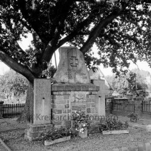 Lindenstraße: Ehrenmal mit Einfriedung, Baum und Blumenschmuck: im Hintergrund Häuser