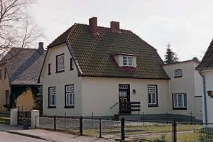 Hasselbusch: giebelständiges Wohnhaus: Straßenfront: Traufseite mit Eingangstür, rechts Anbau: Vorgärten, Gartenzäune