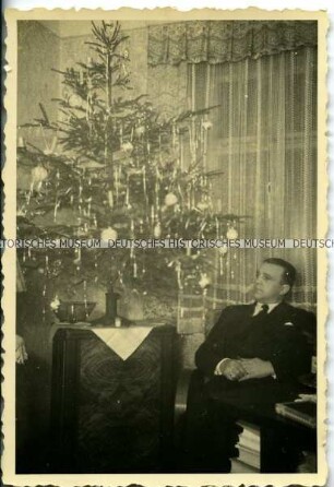 Mann sitzt neben einem Weihnachtsbaum