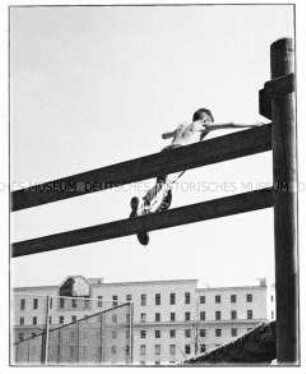 Junge springt von einem Holzbalken (Altersgruppe 18-21)