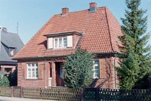 Kamp 19: traufständiges Wohnhaus aus Backstein: Straßenfront: Eingangsloggia, darüber Flachgaube: Jägerzaun, Gartenpforten