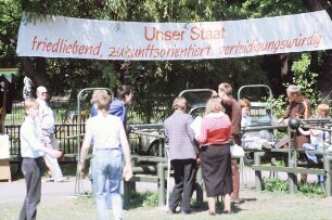 Passanten unter Spruchband "Unser Staat - friedliebend, zukunftsorientiert, verteidigungswürdig"