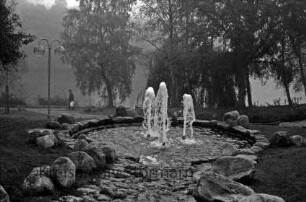 Neuhöfer Park: Springbrunnen: dahinter Weg und Bäume: links Straßenlampe und Mann: hinten Neuhöfer Teich