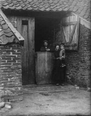 Familie am Tor : Eine Familie am Tor eines Hauses stehend.