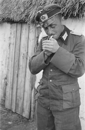 Zweiter Weltkrieg. Zur Einquartierung. Sowjetunion. Angehöriger der deutschen Wehrmacht beim Rauchen vor einer Bauernhütte