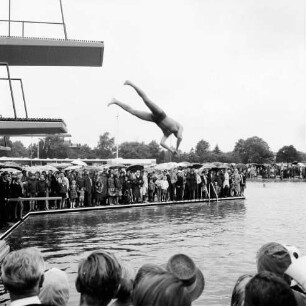 Sommerbad Tarpenbek: Am Hallenbad: Eröffnung: Person springt vom Sprungturm, Gäste am Rand des Schwimmbeckens