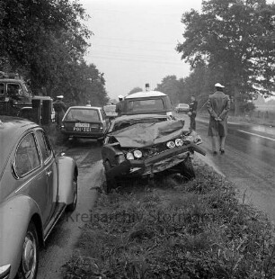 Verkehrsunfall: Landesstraße zwischen Bargteheide und Hammoor: Zusammenstoß von zwei Personenwagen: nasse Fahrbahn: am Straßenrand Pkw mit eingedrücktem Vorderteil: Einsatzwagen von Polizei und Freiwilliger Feuerwehr, Polizisten: Polizist und Feuerwehrmann auf Straße: links Hofeinfahrt, 19. August 1980