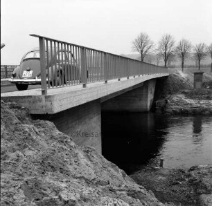 Trave: Brückenneubau: Spannbetonbrücke nach Fertigstellung: links VW-Käfer: hinten rechts Baumreihe