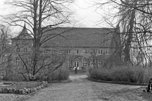 Gut Jersbek: Herrenhaus: Westfassade mit Eingangsportal, Sprossenfenstern, links Turm: davor Rondell mit Figurengruppe: vorne Auffahrt, Bäume, Grünanlage