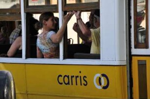 Lissabon - Fahrgäste : Fahrgäste öffnen das Schiebefenster in einem historischen Straßenbahnwagen. Aufgenommen in Lissabon am 13. Oktober 2009
