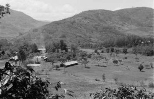 Plantage : Blick über ein in einer Plantage gelegenes Dorf in den Usambara-Bergen; an den Berghängen weitere Hütten