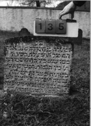 Grabstein 135 (Index: 99798447) Material: Sandstein Zustand: gut, eingesunken Maße HxBxT: 51x54x8 cm Beschreibung: Stele mit flachem Bogenabschluß: Grabstein 135