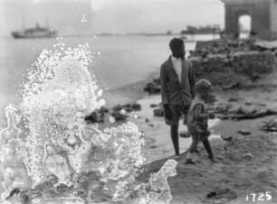 Personen am Strand : Ein kleines Kind und ein junger Mann stehen am Strand