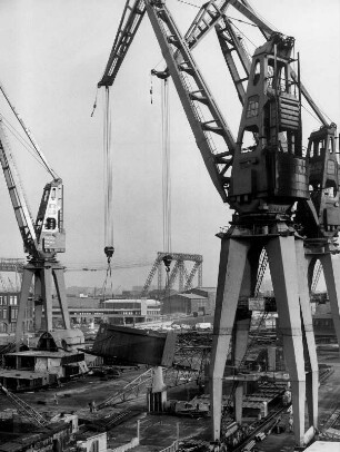 Hamburg. Steinwerder. Blick auf das Gelände der Großwerft "Blohm & Voss". Krane transportieren Teile zum Rohbau eines Schiffes.