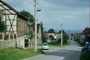 geplasterte Dorfstraße, beidseitig Höfe; Trabant am Straßenrand; Verkaufsstelle