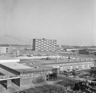 Klosterbergen: Blick von Wohnblock Richtung Nordosten auf neuen Stadtteil: vorn Straße Am Ladenzentrum: dahinter Sachsenwald-Einkaufszentrum mit SPar-Markt: vorn rechts parkende Pkws: links dahinter Baustelle der evangelischen Nathan-Söderblom-Kirche mit Baukran: hinten links Wohnblock an der Bogenstraße: hinten Mitte mehrgeschossiges Punkthaus: hinten rechts Reihenhäuser und Gebäude der Volksschule Klosterbergen an der Klosterbergenstraße: