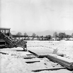 Baustelle: Baustopp wegen Wintereinbruch: links Baggerschaufel: dahinter zwei weitere Bagger und Pkw: vorn rechts Bretterstapel: in der Mitte Eisengittermatten: hinten Knick: Winter