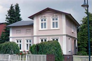 Hauptstraße 39: giebelständiges Wohnhaus mit Querbau und umlaufendem Gesims: Straßenfront: Traufseite mit Eingang: vorne Gartenzaun
