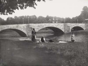 Rochlitz, Straßenbrücke über die Zwickauer Mulde. Familie mit zwei Kindern am Ufer des Flusses beim Bettenlüften