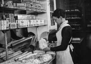 Dresden-Altstadt, Webergasse 35. Feinbäckerei und Conditorei Firma "Hermann Angermann", Inhaber Franz Seraph Schmid. Christstollenbäckerei. Verpacken der Übersee-Versandstollen durch eine Verkäuferin. Im Regal Edelwaffeln der Marke "Flirt" der Firma W. Hromadka, Jäger Nachfolger und "Goldschneiders Gluten-Zwieback"
