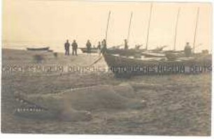 Strand mit Booten und Sandskulptur