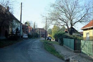 Dorfstraße im Ortskern; gepflasterter Gehweg, Häuser