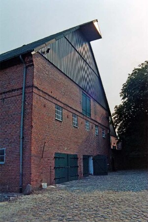 Fritz-Berodt-Straße 7-9: Hofanlage: westliches Wirtschaftsgebäude: Giebelseite: unten Stalltore, oben Luke, Giebel mit Verbretterung, an Spitze Seilwinde: davor Vorplatz mit Kopfsteinpflaster, rechts Baum: 19. August 1993