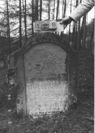 Grabstein 128 (Index: 99608812) Material: Sandstein Zustand: sehr stark verwittert mit großem Textverlust Maße HxBxT: 103x72x11 cm Beschreibung: Stele mit geschwungenem Rundbogen, vertiefter Textteil mit Rundbogen: Grabstein 128