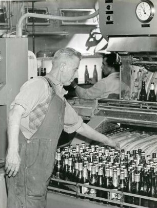 In einer Brauerei. Flaschen werden in einer Reinigungsanlage gespült. Ein Arbeiter kontrolliert