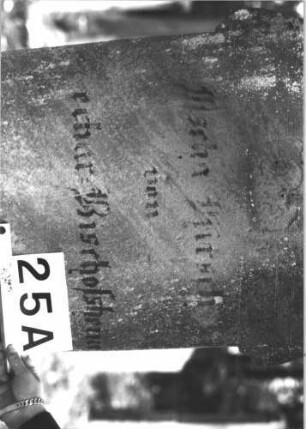Grabstein 25 (Index: 99898731) Material: Sandstein Zustand: fast völlig verwittert Maße HxBxT: 148x57x29 cm Beschreibung: aufgesockelte Stele mit seitlich auskragendem Dreipassbogenabschluss, im Bogen Blüte, unterer Sockel felsartig gearbeitete, Schrift mit schwarzer Farbe nachgezogen Symbolik: Blüte: Grabstein 25A