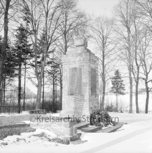Rethwischdorf: Ehrenmal mit Kränzen: dahinter Baumreihe: im Hintergrund Häuser: Winter
