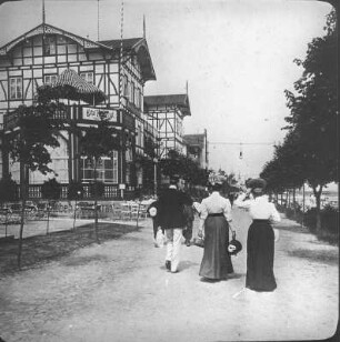 Binz. Strandpromenade mit Spaziergängern. Blick zum Hotel Kaiserhof (ehem. Kurhaus)