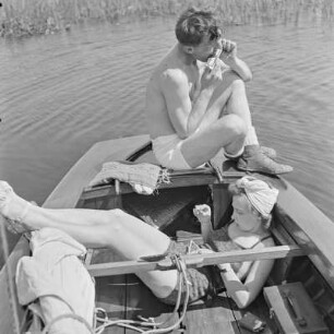 Elisabeth Gremmler liegt in einem Segelboot und oberhalb von ihr spielt ein befreundeter Mann Mundharmonika