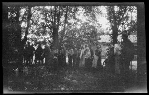 Gruppe von vor Bäumen im Halbrund stehenden einheimischen Männern und Frauen