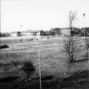 Sportplatz Am Exerzierplatz: Personen beim Weitsprung, dahinter Gebäude der Gemeinschaftsschule Harksheide: Blick von Westen