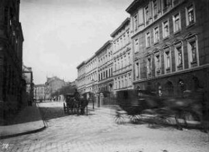Rechte Bildseite - Wohnhäuser. Bildmitte - Straße mit vorbeifahrenden Kutschen